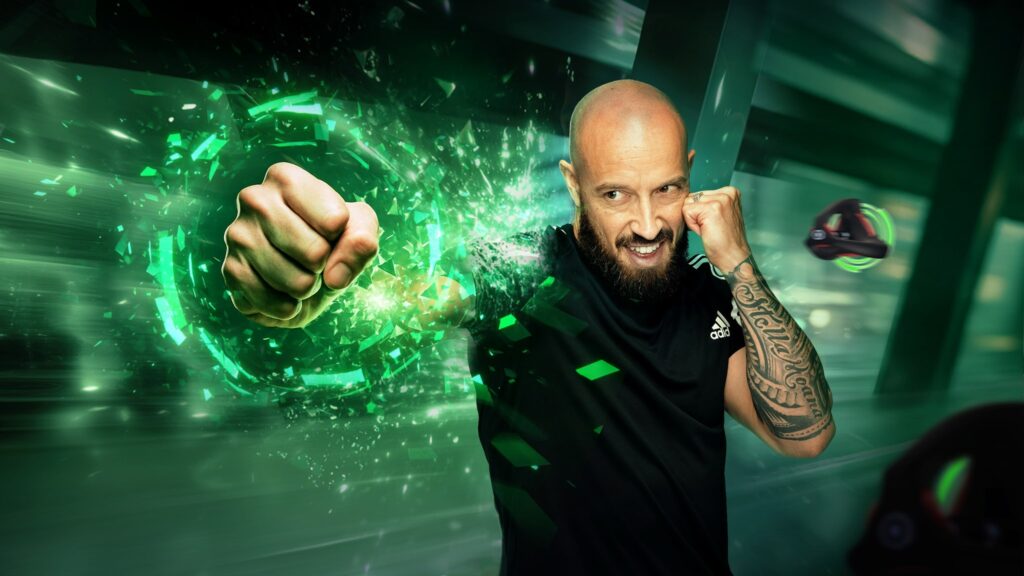 Les Mills BodyCombat VR promotional image showing a fitness instructor punching forward, creating shattering green digital energy effects.